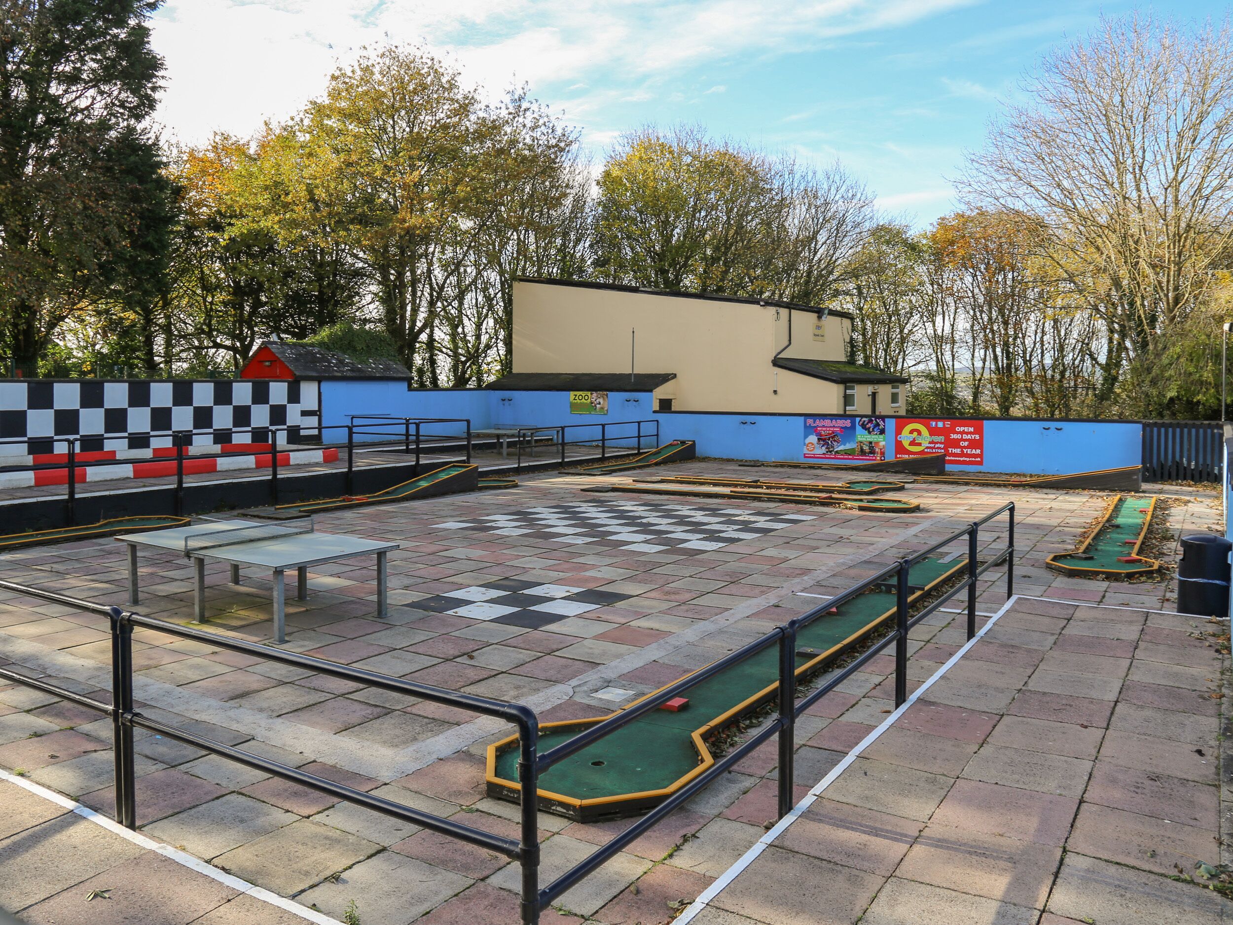 An outdoor billiards area with tables, railings, and a checkered floor pattern.