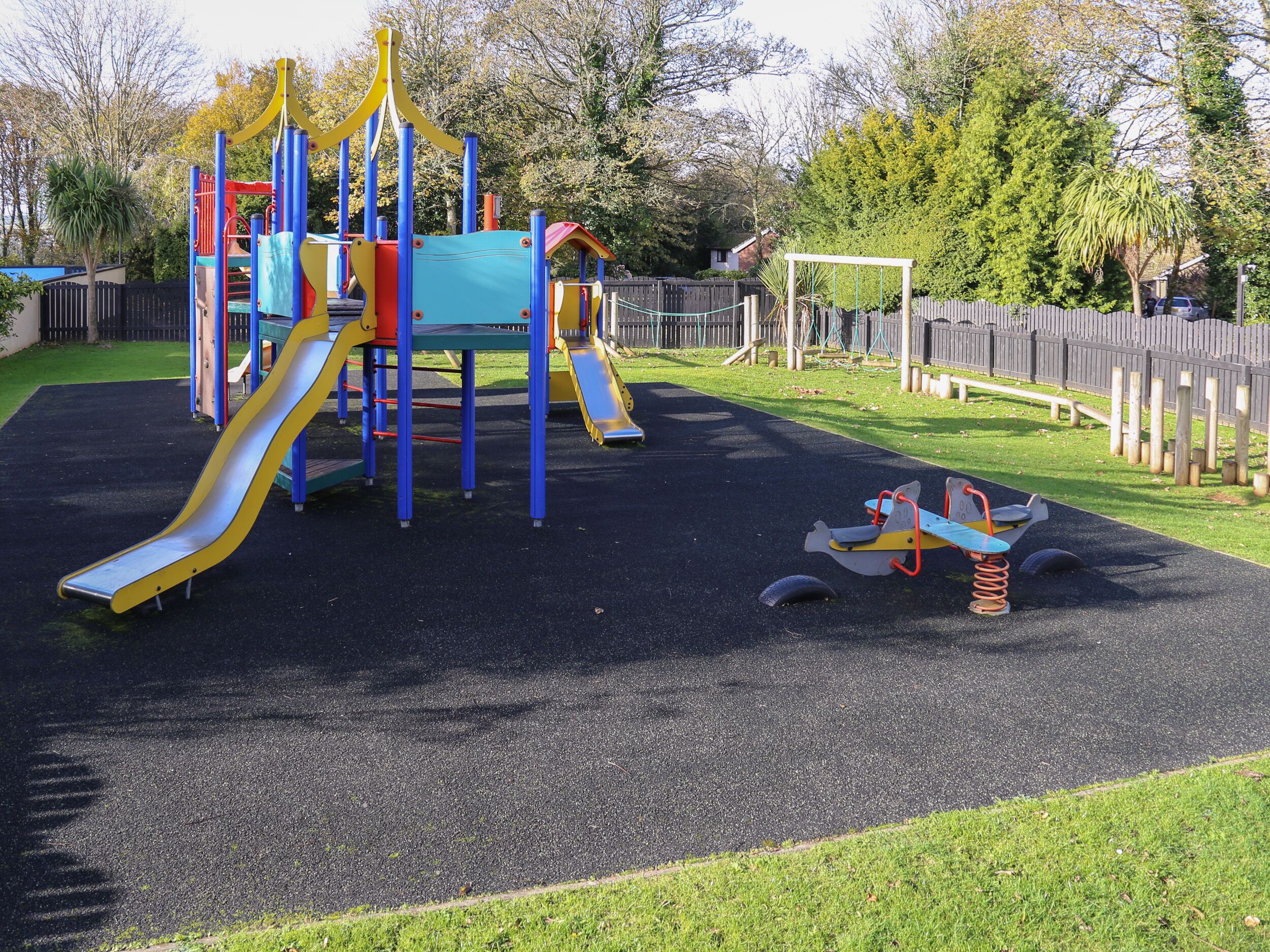 A playground with a slide, climbing structures, and a seesaw.