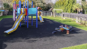 A playground with a slide, climbing structures, and a seesaw.