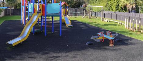 A playground with a slide, climbing structures, and a seesaw.