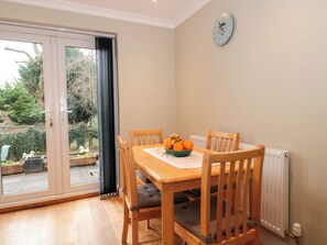 A dining area with a wooden table, four chairs, and a bowl of oranges. - The Seventeen (Cheltenham)