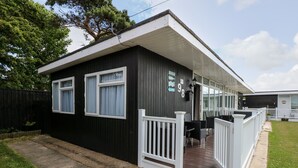 A small, single-story house with a porch, a welcome mat, and a fenced yard. - 98 Cherry Park (Skegness)