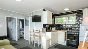 A compact living space with a kitchenette, a dining area, and a seating area. - 98 Cherry Park (Skegness)