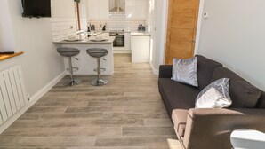 A modern kitchen with a TV, two bar stools, and a wooden door. - Afon Rhos Bach (Caernarfon)