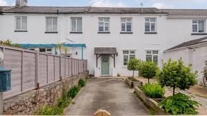 A traditional white building with a central entrance, a stone wall on one side, and a paved pathway leading to the entrance. - Martingale (Torquay)