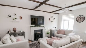 A living room with a fireplace, a television, and a clock on the wall. - Martingale (Torquay)