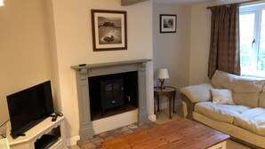 A living room with a fireplace, a television on a stand, a sofa, and a coffee table.