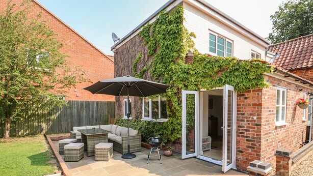 A patio with outdoor furniture, a table, and an umbrella.