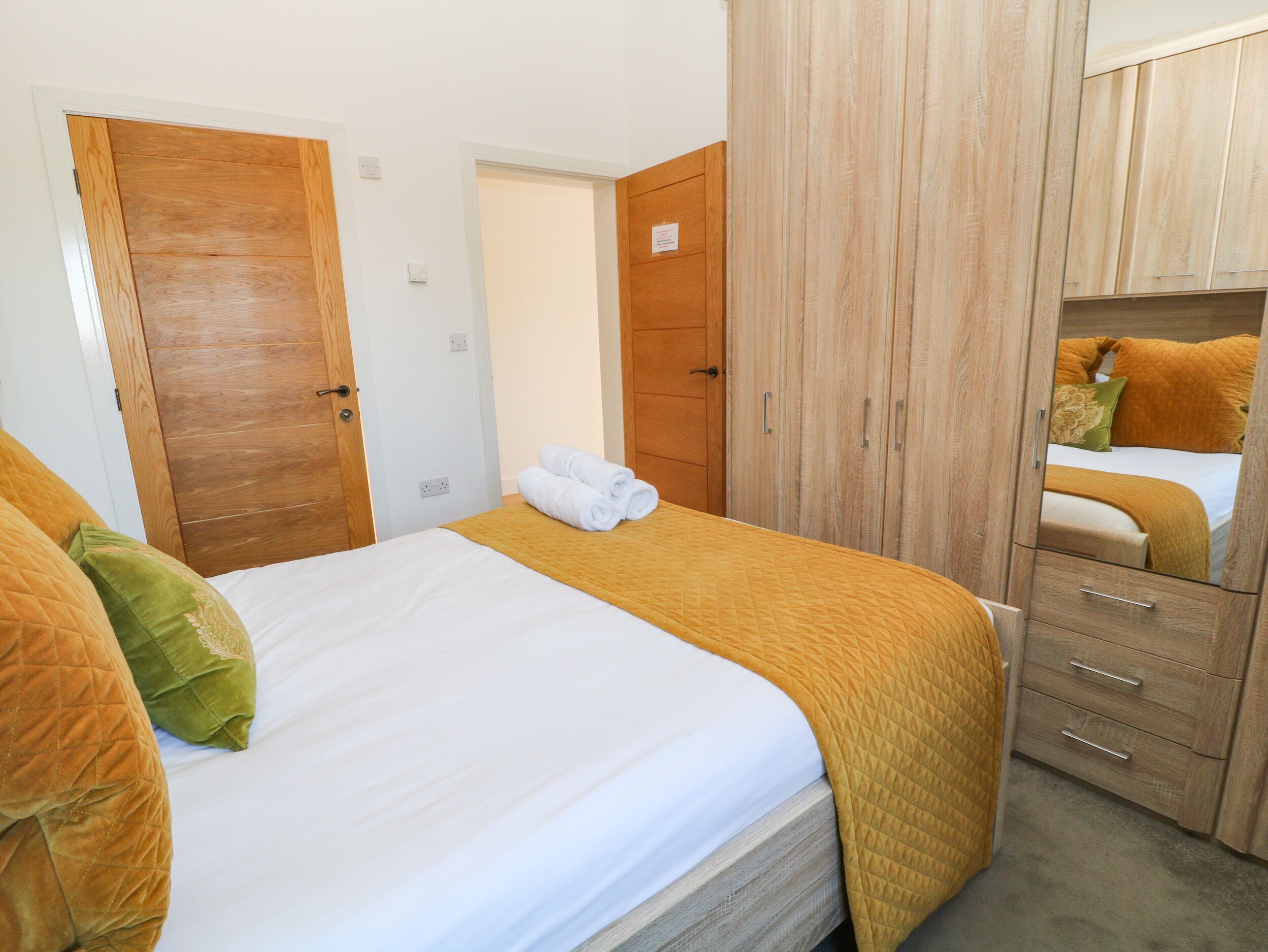 Un dormitorio con cama, armario y espejo.