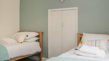 A bedroom with two beds, a wardrobe, and a decorative heart on the wall.