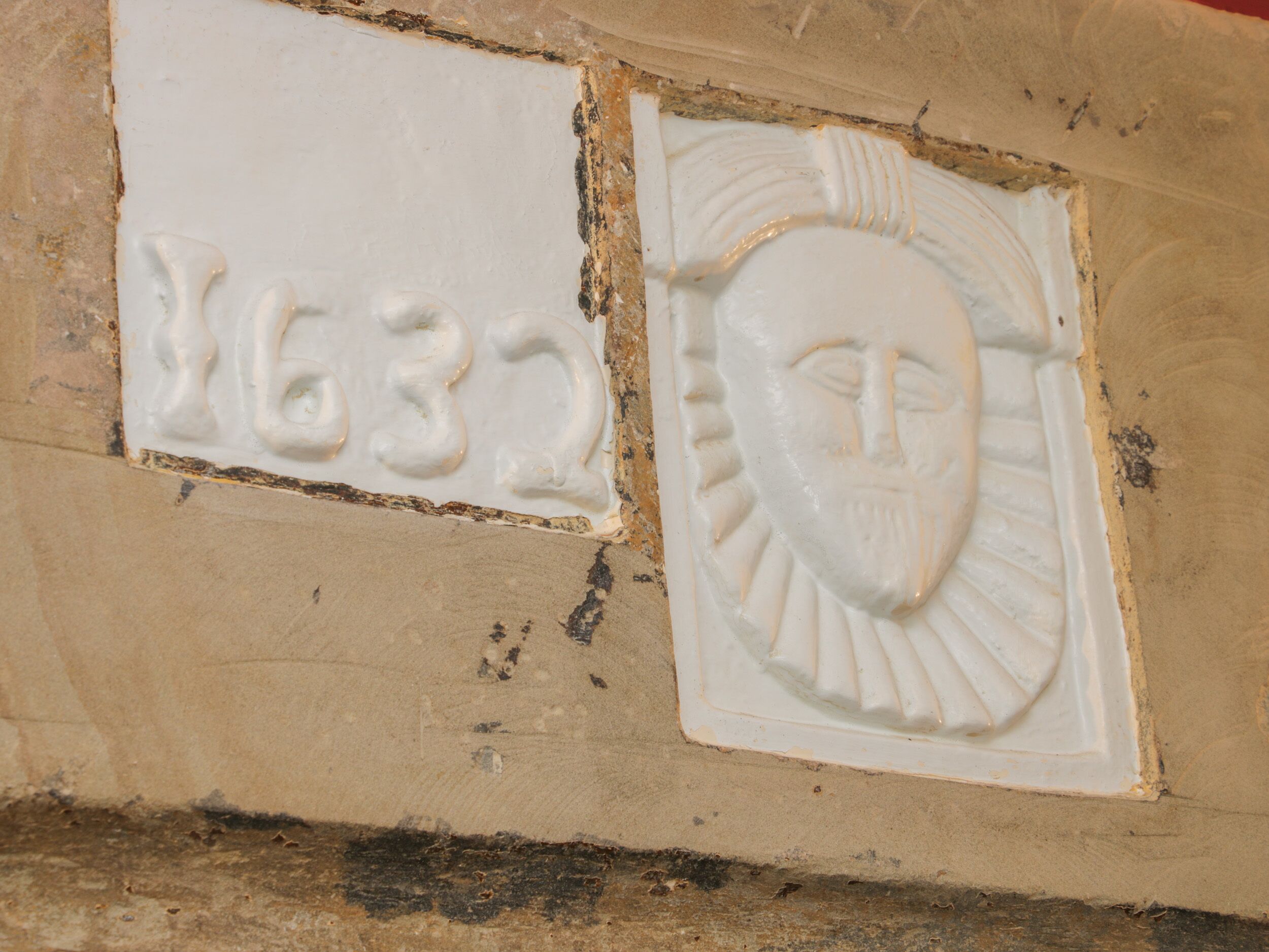 A wall with two distinct reliefs: one with the number '1632' and another with a face.