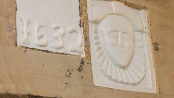 A wall with two distinct reliefs: one with the number '1632' and another with a face.