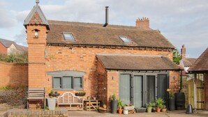 A brick house with a tower, large windows, and a garden with potted plants. - Bank House Barn (Shrewsbury)
