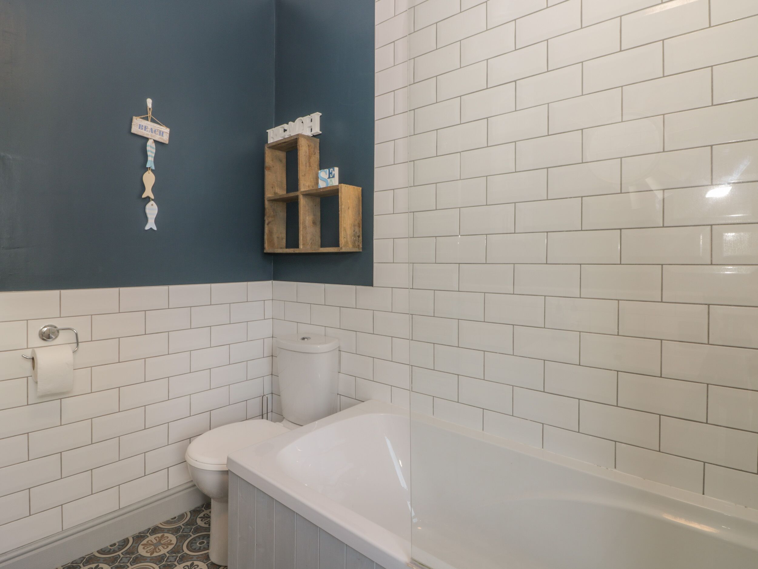 A bathroom with white subway tiles, a bathtub, a toilet, and a towel rack.
