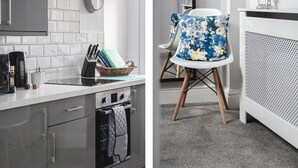 A modern kitchen with a built-in oven, a coffee maker, and a basket of books on the counter. - Oxford House (Llandudno)
