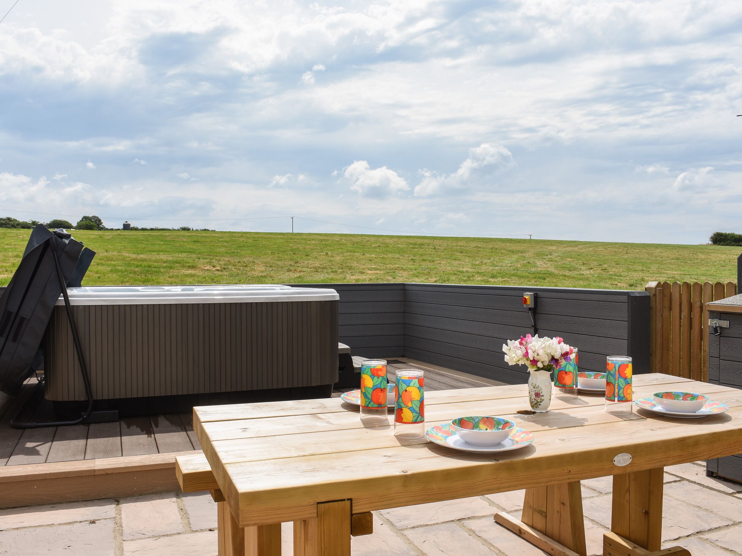 Een terras buiten met een houten eettafel, omgeven door een zwart terras.