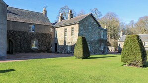 A stone building with a large lawn and two well-trimmed hedges.