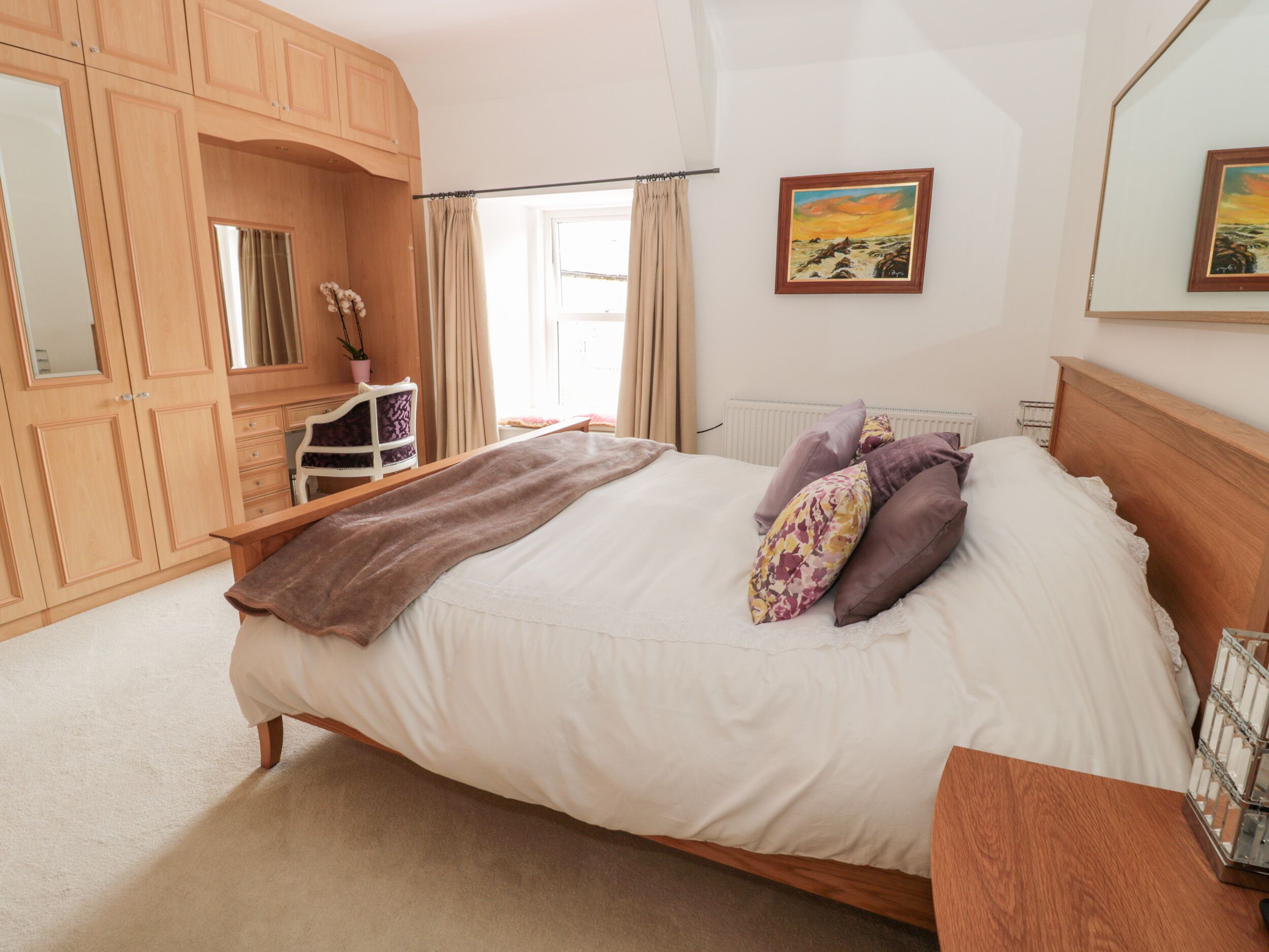 Une chambre à coucher avec un lit, une armoire en bois et une fenêtre avec des rideaux.