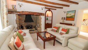 Ein Wohnzimmer mit Kamin aus Stein, weißen Sofas und einem Holztisch.