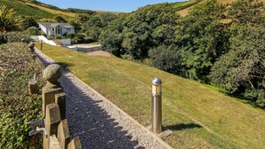 A pathway leading to a house with a pool, surrounded by lush greenery and hills. - 2 Garden Apartment (Kingsbridge)