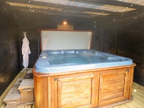 Un jacuzzi en una habitación de madera con un banco y un perchero para bata.