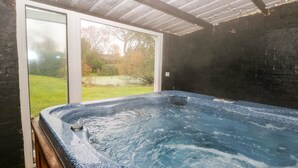 Ein Whirlpool mit Holzterrasse und Glastür zum Garten.