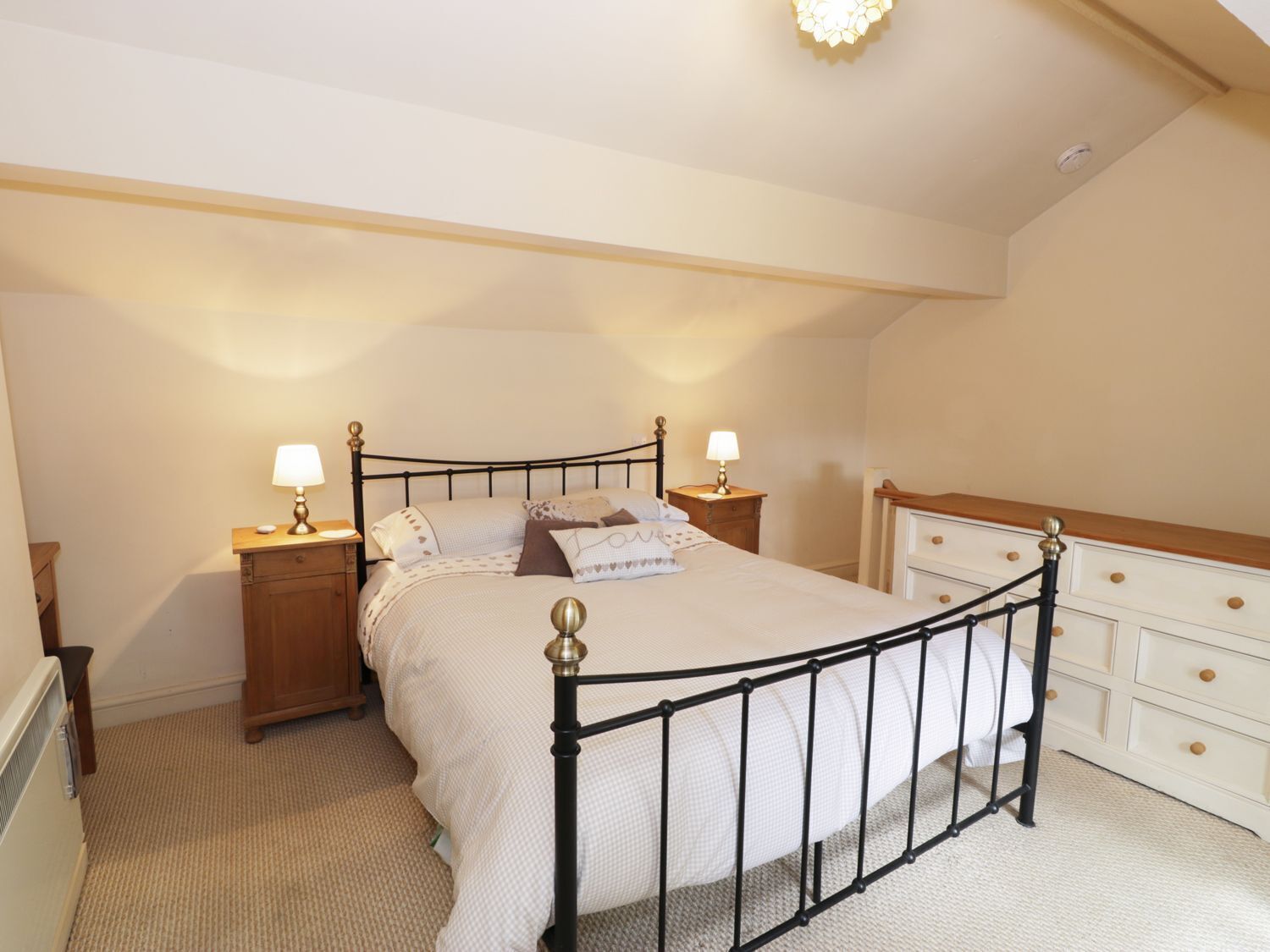 A bedroom with a single bed, bedside tables, a dresser, and a ceiling light fixture.