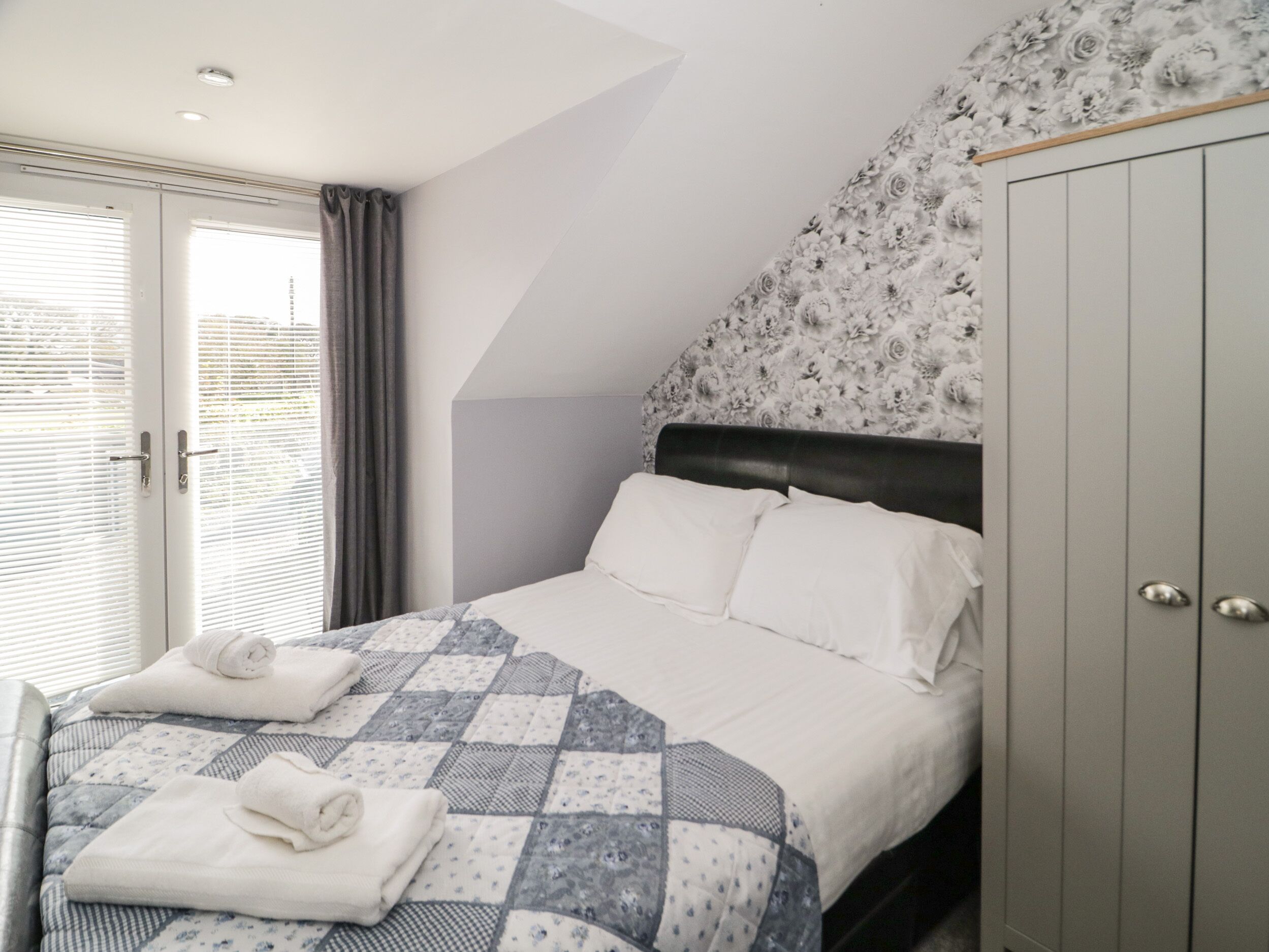 A bedroom with a bed, a wardrobe, and a window with curtains.