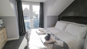 Une chambre à coucher avec un lit, une commode et une vue à travers une porte vitrée.