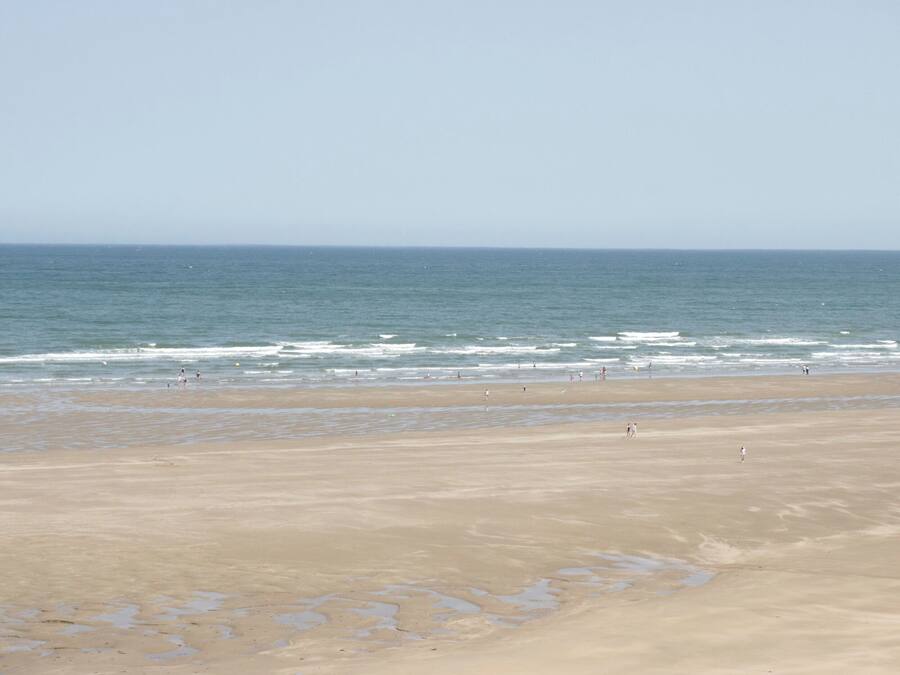 A wide beach with a clear view of the ocean and a sandy shore.
