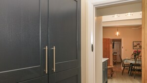 A modern kitchen with dark cabinets and a dining area with a table and chairs. - 3 Old Hall Cottages (Bakewell)