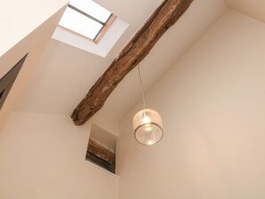 A room with a sloped ceiling, exposed wooden beams, a skylight, and a hanging light fixture. - 3 Old Hall Cottages (Bakewell)