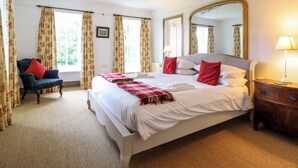 A neatly arranged bedroom with a large bed, a chair, a bedside table with a lamp, and a mirror on the wall. - Mor Edrin (Talsarnau)