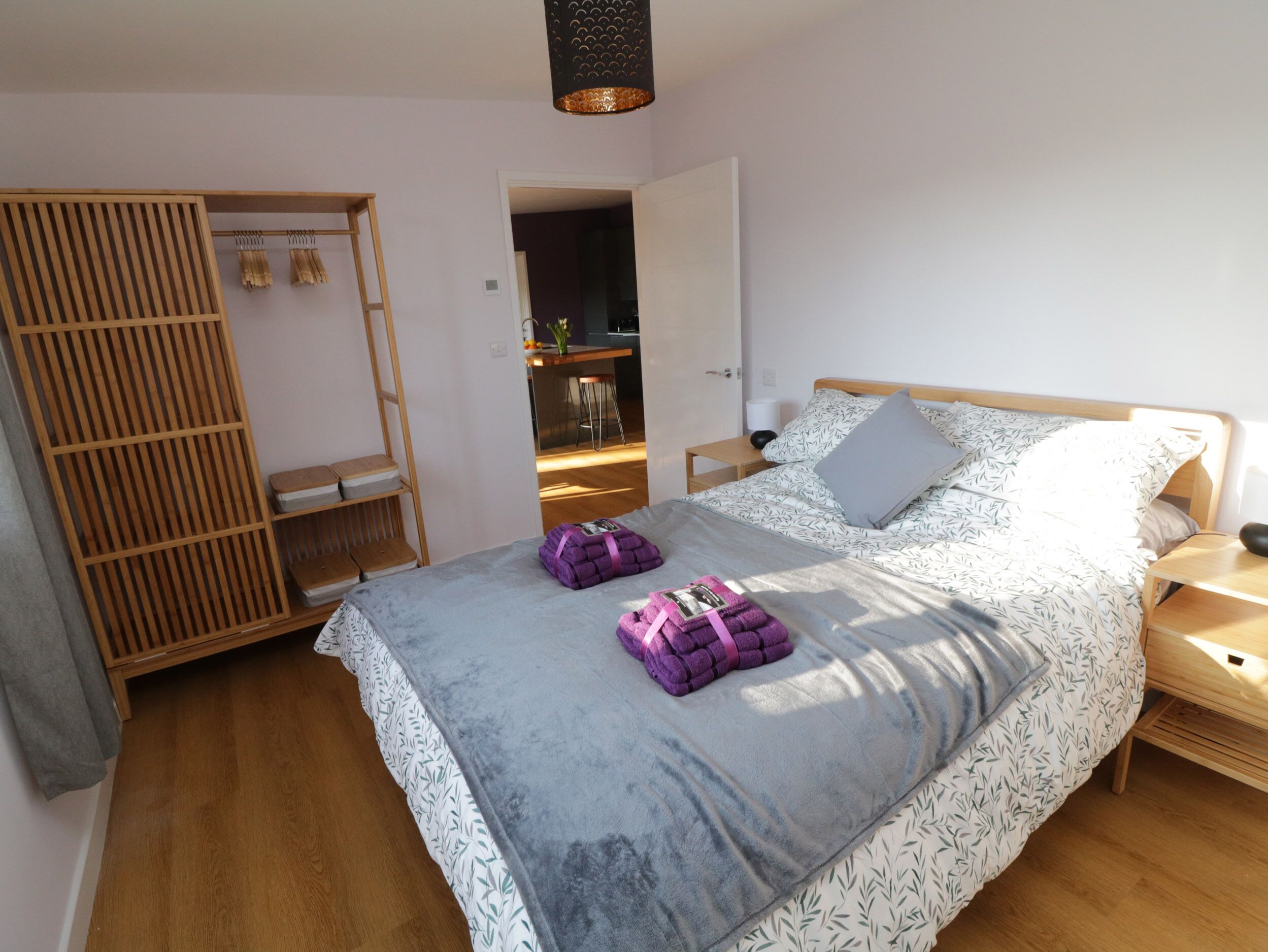A bedroom with a bed, a wardrobe, and a small kitchen area.