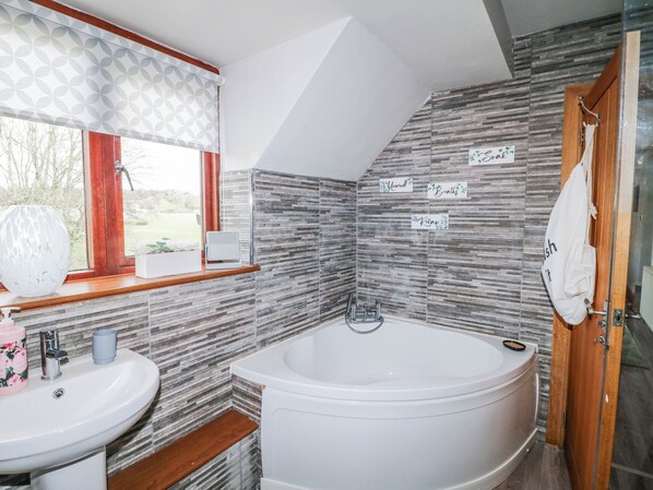 Une salle de bain avec une baignoire, un lavabo et une fenêtre donnant sur un beau paysage.
