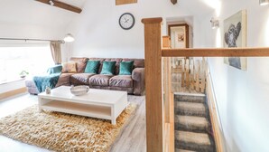 A living room with a sofa, coffee table, and a staircase with a wooden railing. - Fields Farm (Stoke-on-Trent)