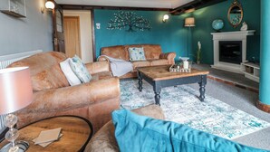 A living room with a fireplace, a wooden ceiling, and a teal accent wall. - Fields Farm (Stoke-on-Trent)