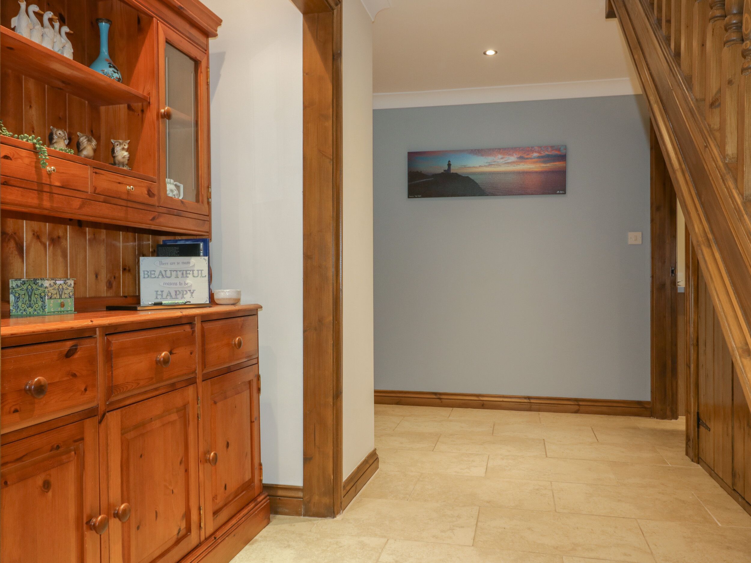 A hallway with wooden cabinetry, a decorative sign, and a painting on the wall.