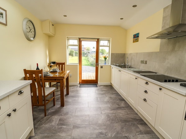 A kitchen with a dining area, featuring a stove, cabinets, and a window with a view of the outdoors.
