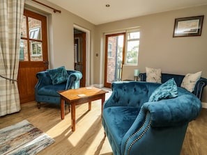 A living room with two blue sofas, a wooden coffee table, and a patterned rug.