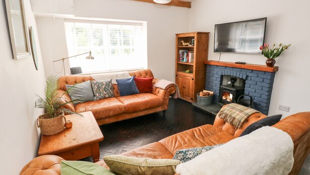 Een gezellige woonkamer met een leren bank, een houten bijzettafeltje en een open haard.