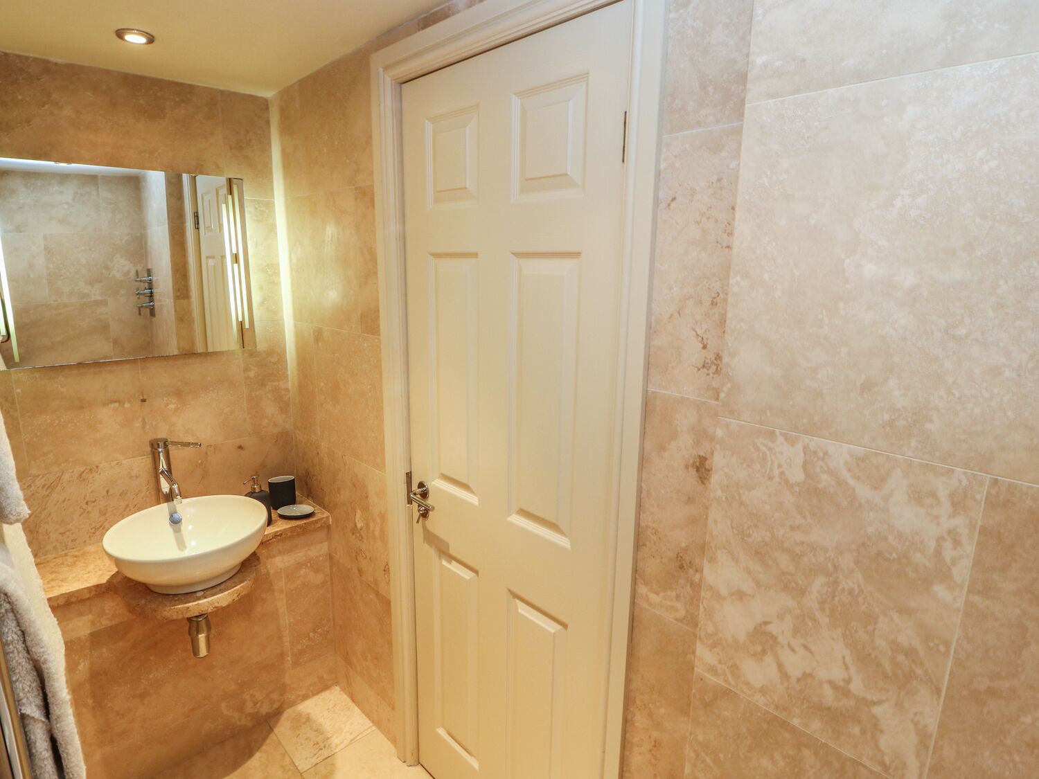 A bathroom with a white door, a sink, and a mirror.