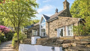 A stone house with a white exterior, a stone wall, and a paved driveway. - Yr Hen Ysgol, The Old School (Porthmadog)