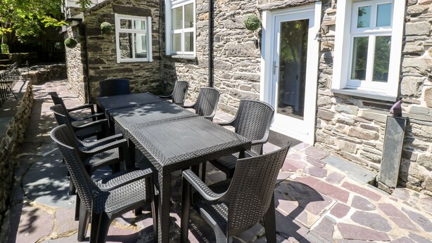 A stone building with a patio area featuring a table and chairs. - Yr Hen Ysgol, The Old School (Porthmadog)