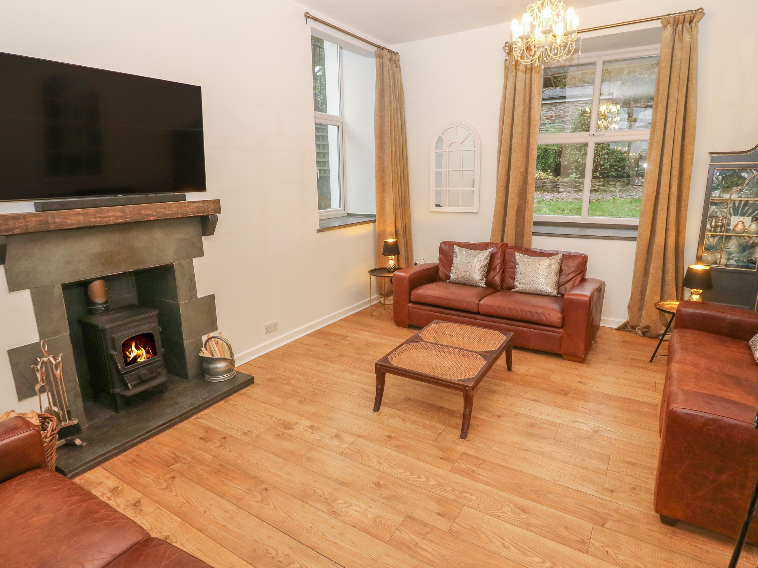 Una sala de estar con chimenea, sofás de cuero, una mesita de centro y un televisor.
