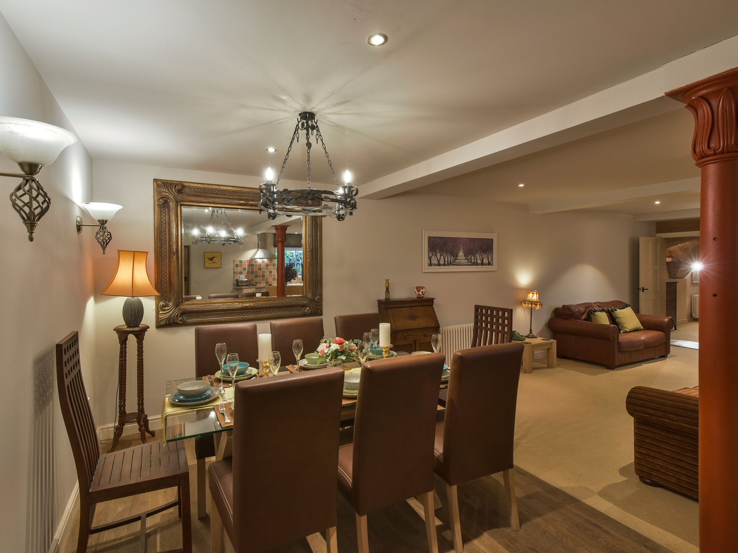 A dining area with a chandelier, a large mirror, and a dining table set for six.