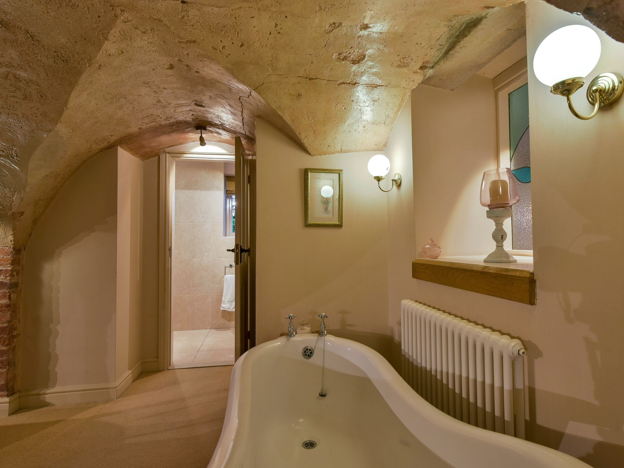 Une salle de bain avec une baignoire sur pieds, un radiateur et un tableau encadré au mur.