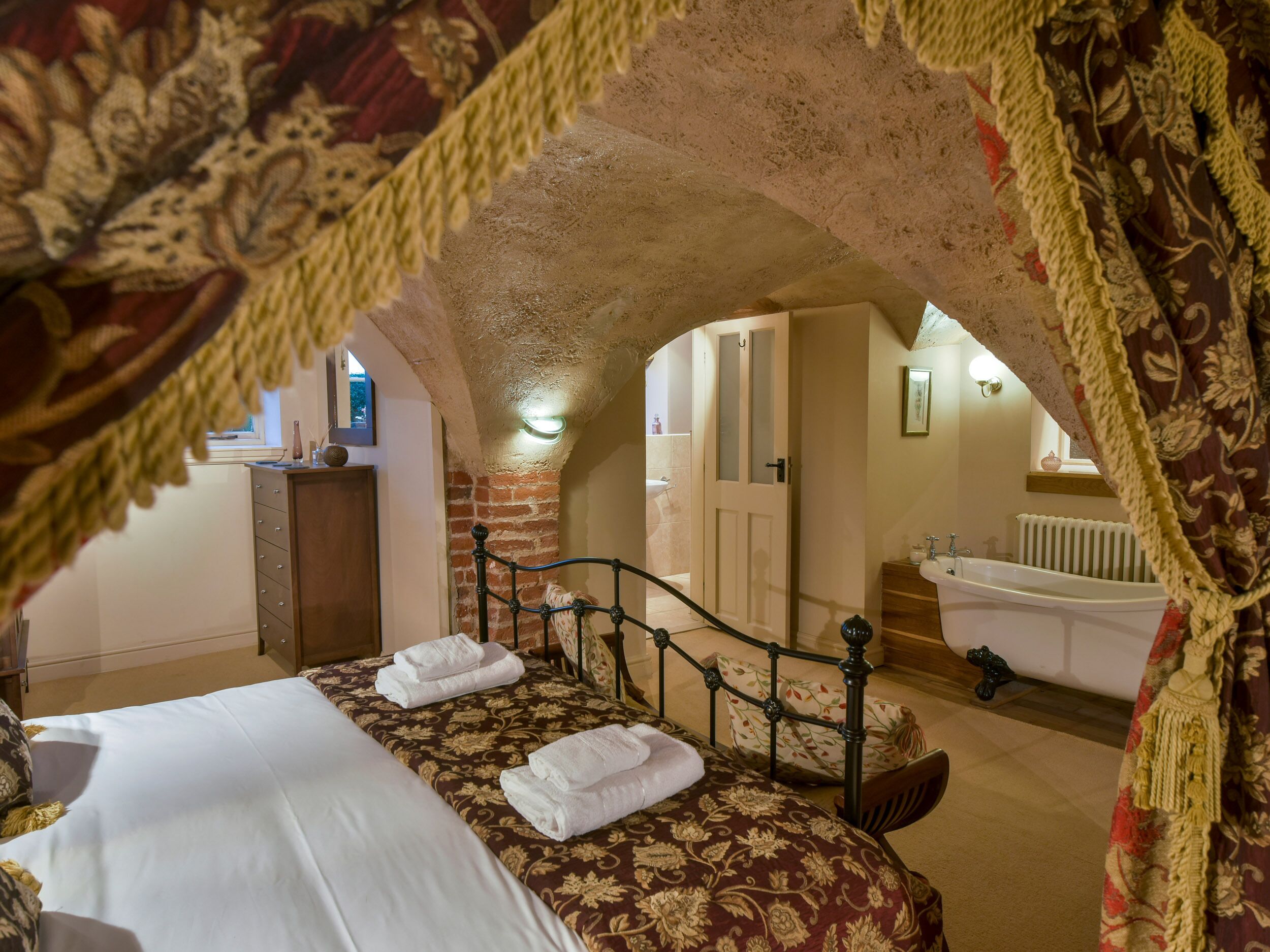 Un dormitori amb un llit, un armari de fusta, un bany amb banyera i una finestra.