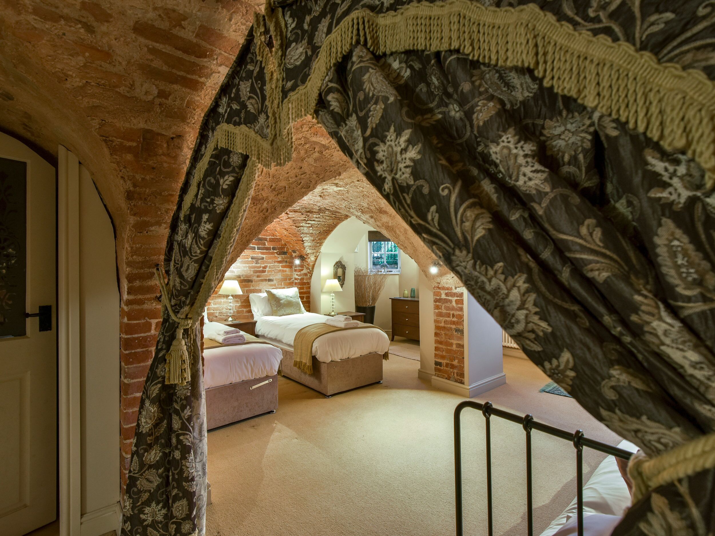 Un dormitorio con techo inclinado, paredes de ladrillo visto y un ventanal grande.