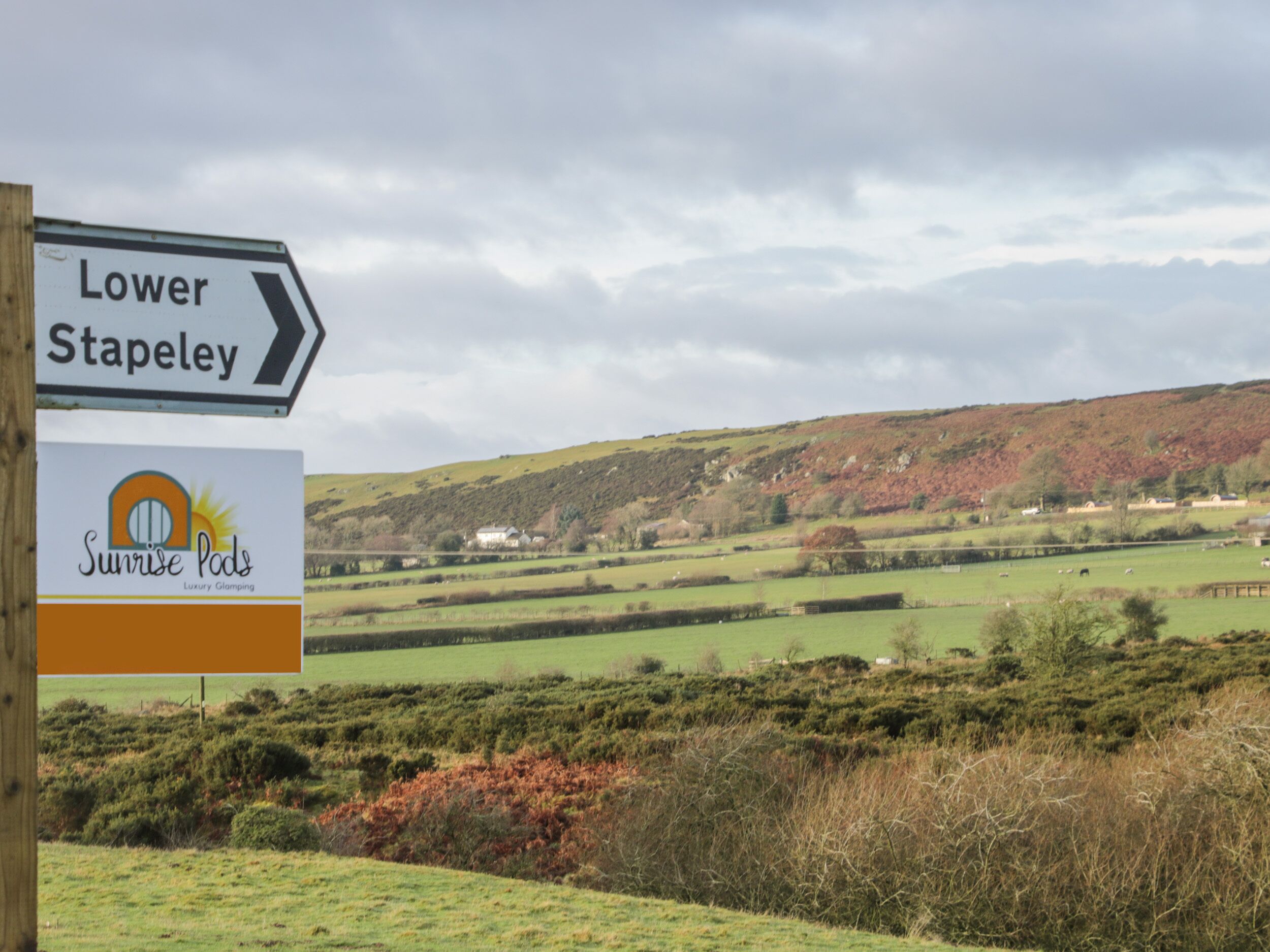 Un panneau indiquant la direction de Lower Stapley, avec le logo de Sunrise Pods.